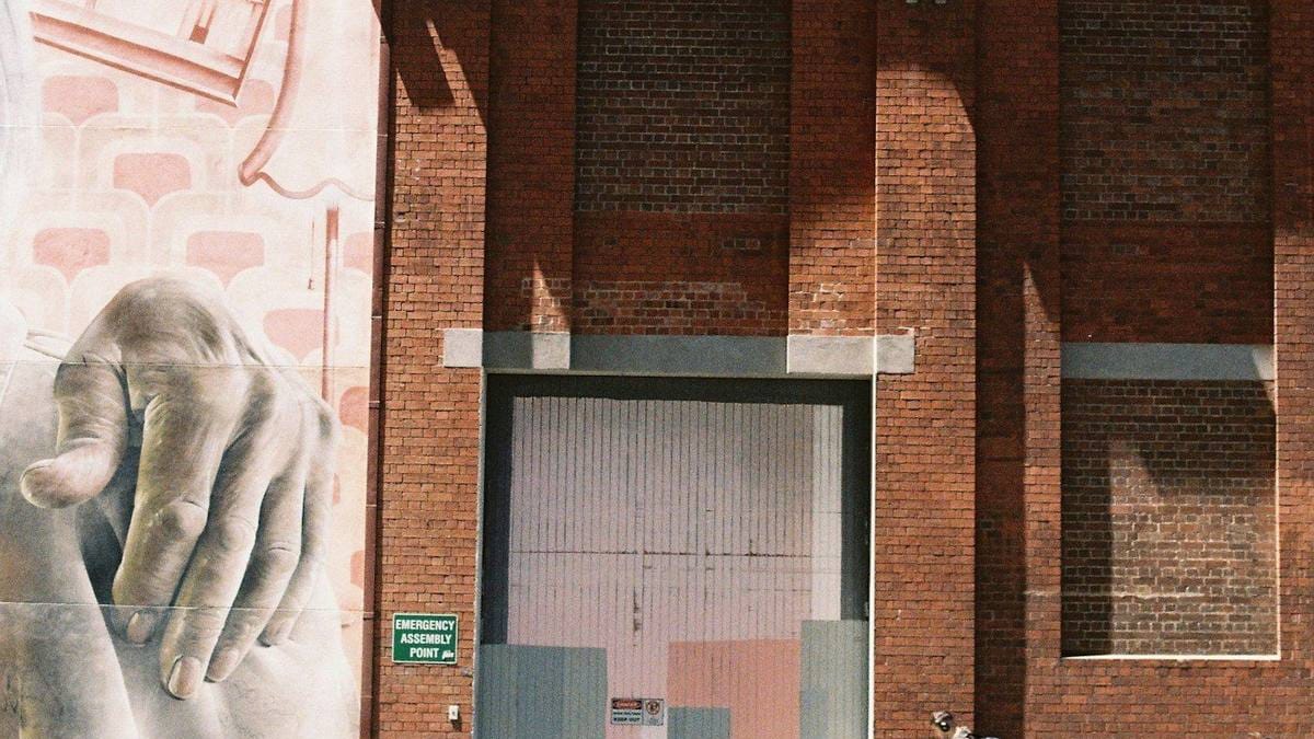 A large mural of a hand painted on the brick side of a heritage civic building.