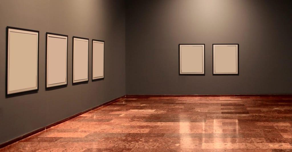 A gallery room with six empty frames arranged across two walls.
