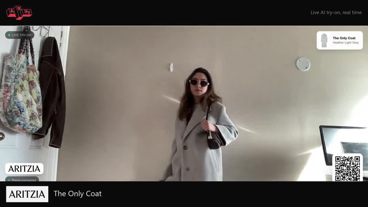 A shopper trying The Only Coat on live at the AI mirror, rendered from her own phone.